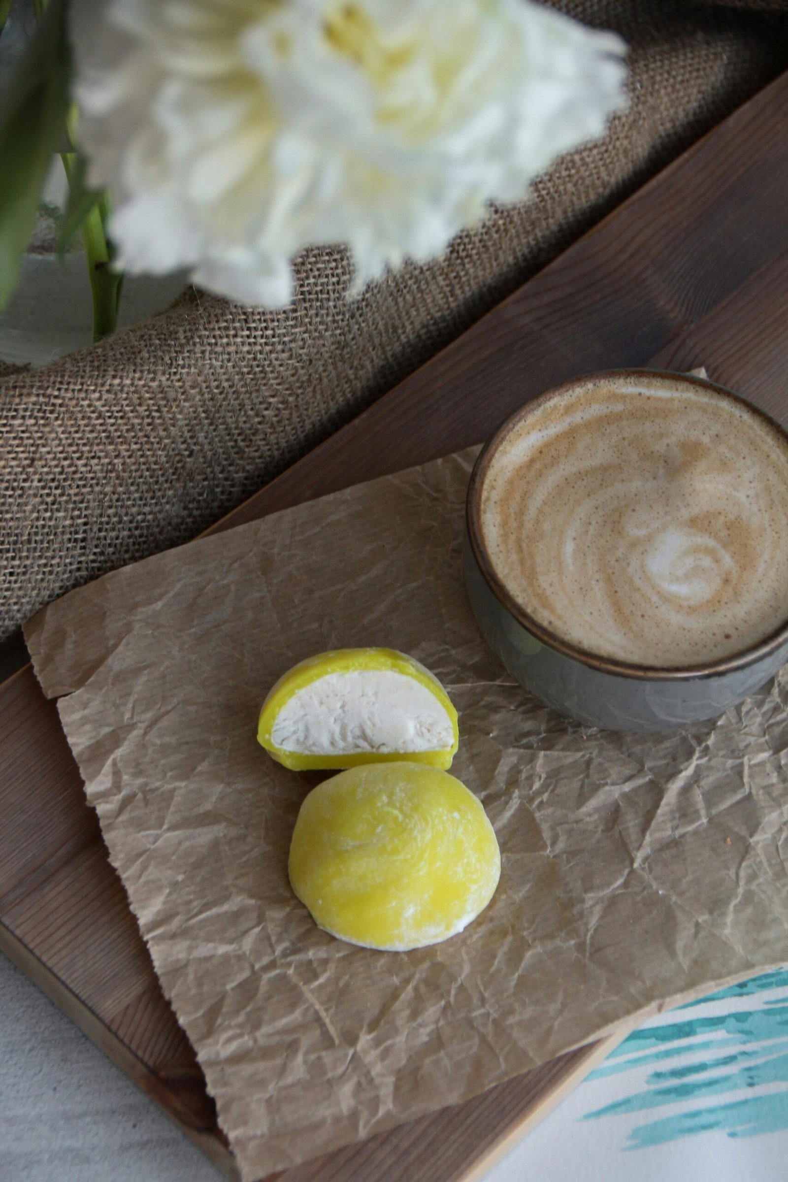 Delightful pairing of cappuccino and sweet mochi on textured surface, perfect for breakfast or snack.