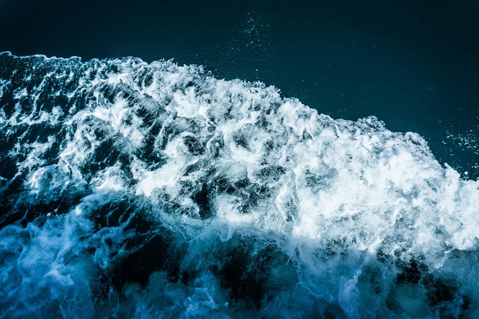Close-up of a dramatic ocean wave with white foam and splashes, showcasing motion and energy.