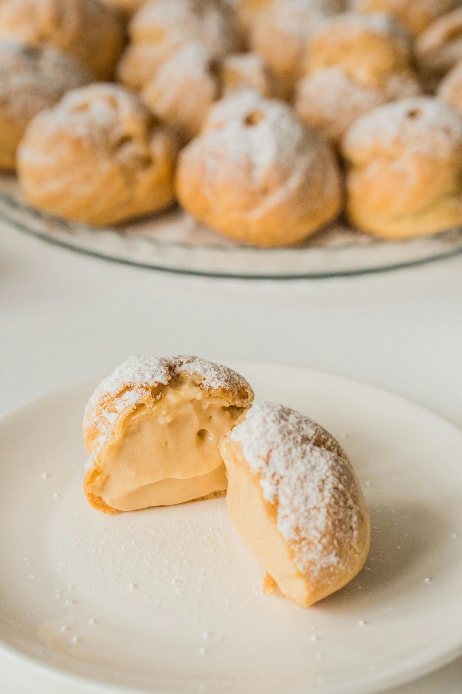 Close-up of cream-filled pastries dusted with powdered sugar on a white plate.