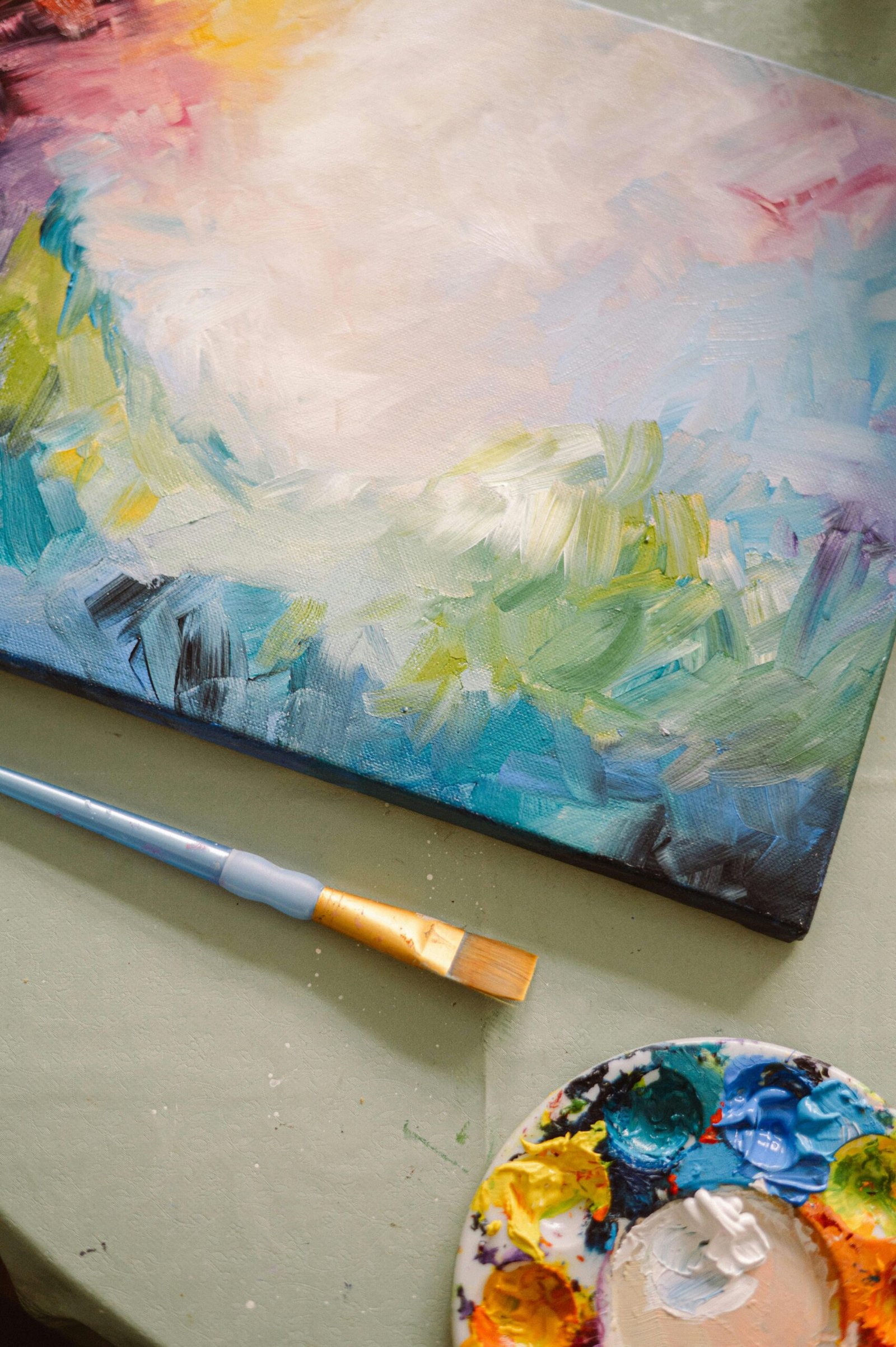Vibrant abstract painting in progress with paint palette and brush, capturing creativity.