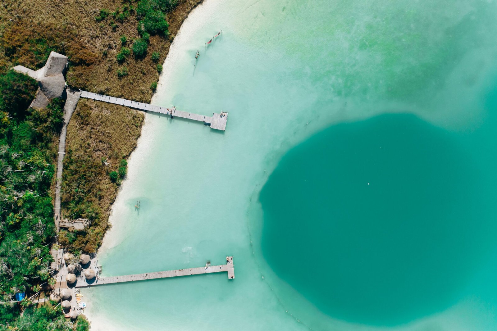 Stunning aerial view of a tropical beach with turquoise water, docks, and lush vegetation.