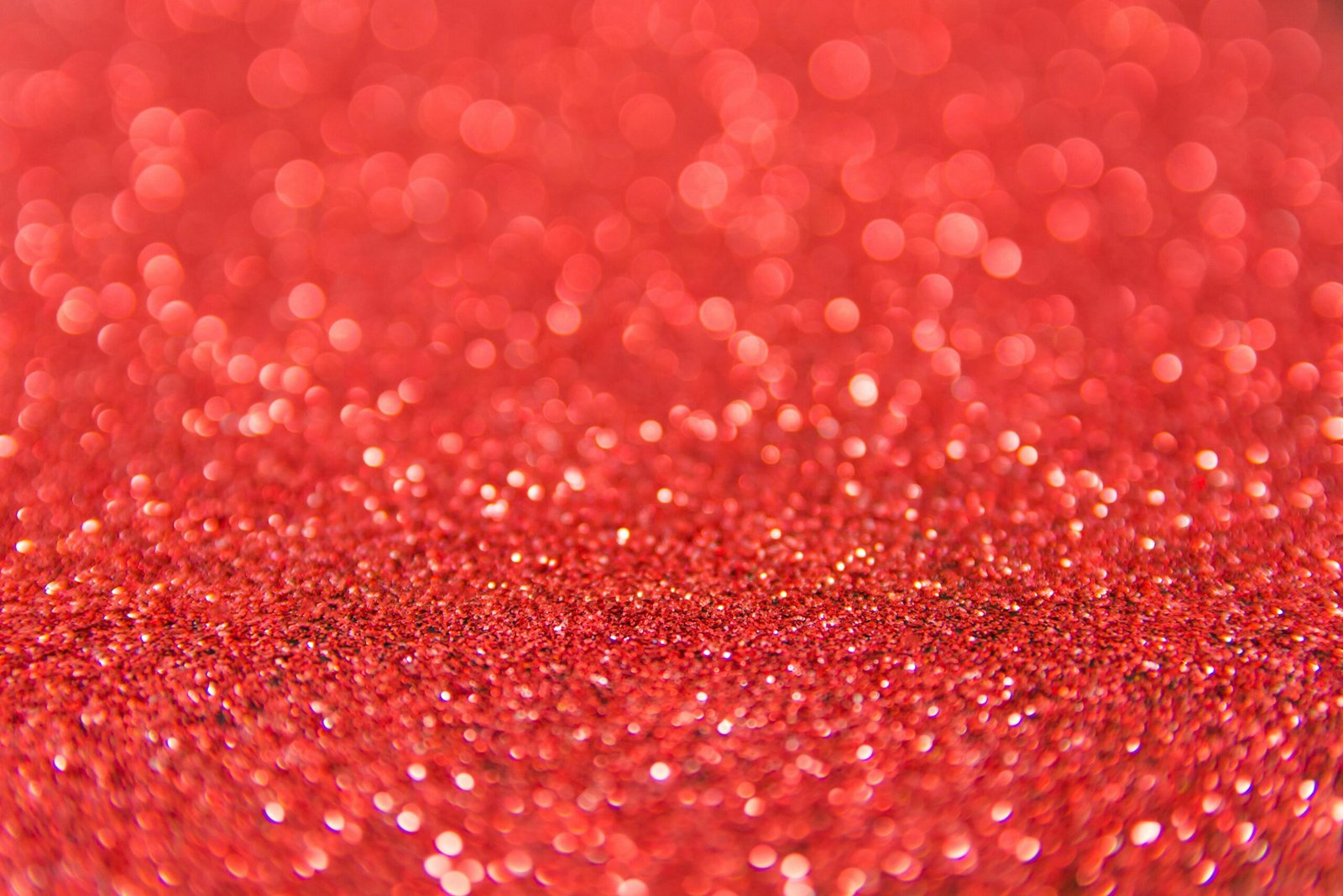 Shimmering red glitter with bokeh effect, ideal for festive backgrounds.
