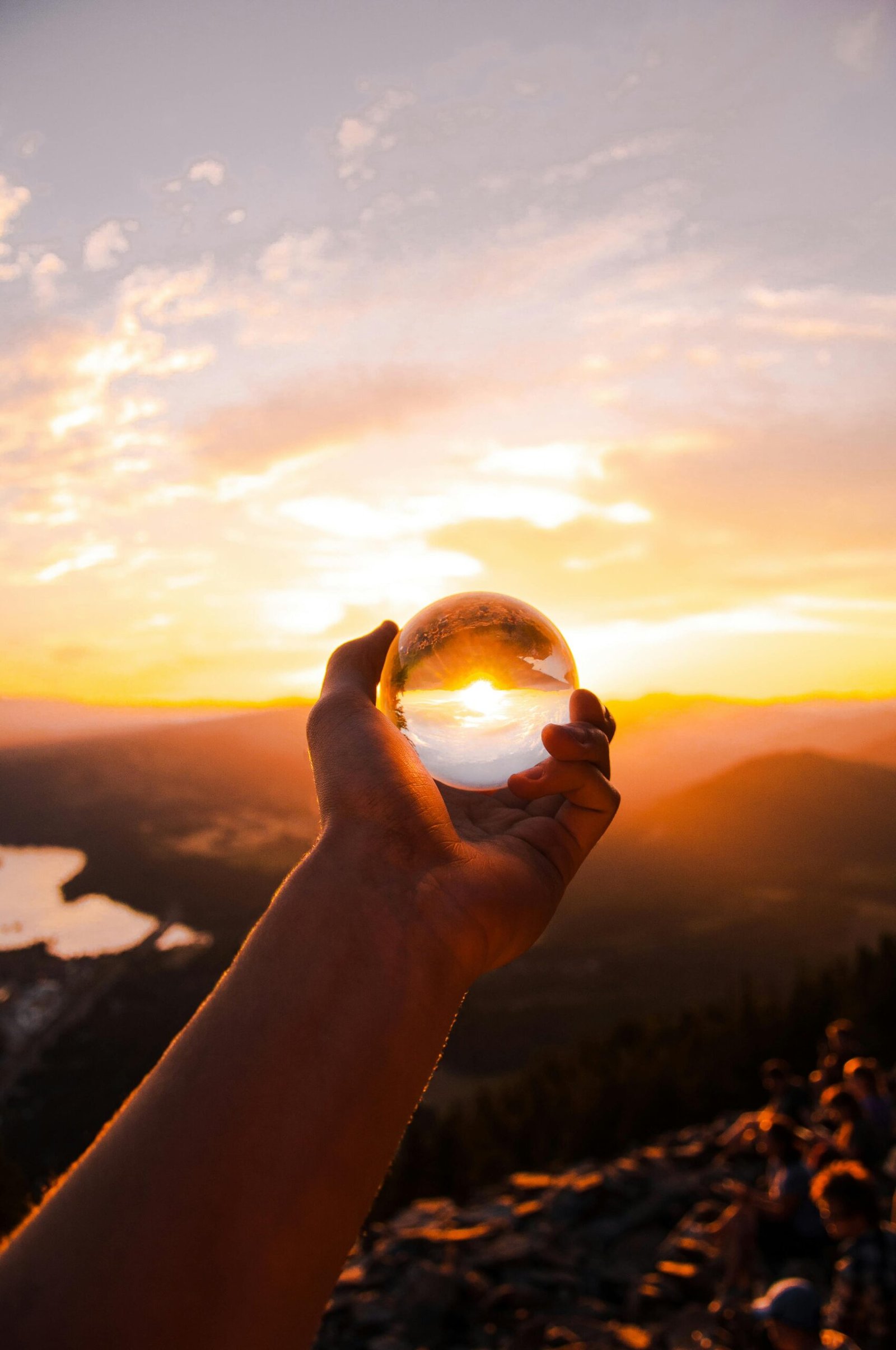 Captivating sunset view reflected in a crystal ball held by hand, overlooking a scenic landscape.